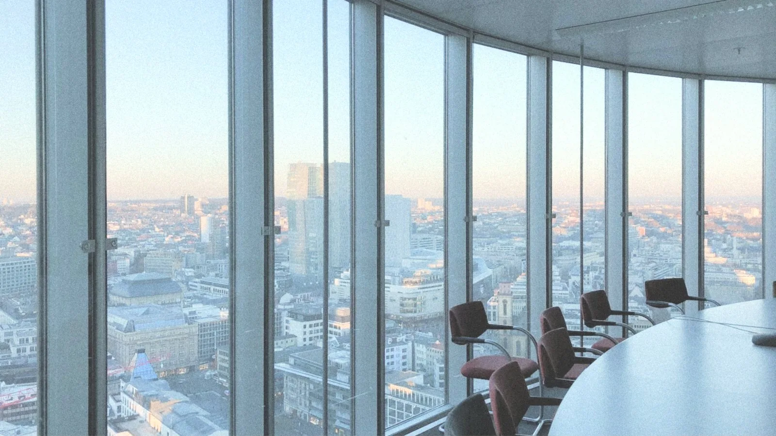 Sala de consejo en lo alto de una torre, con la ciudad al atardecer