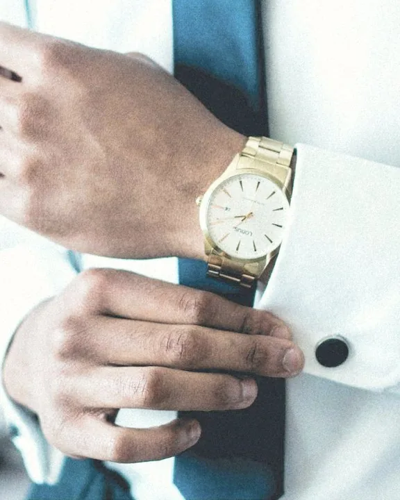 Puño de camisa blanca con gemelo y reloj de oro