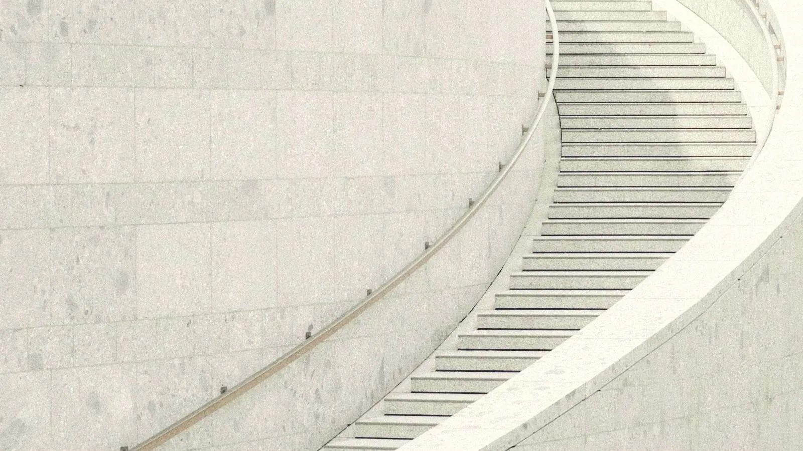 Escalera curva de piedra clara que asciende hacia la luz