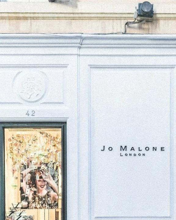Fachada blanca de una boutique con molduras y escaparate iluminado